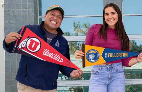 two students holding university pennants standing with Franco Falcon